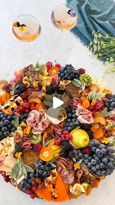 a fruit and vegetable platter with two glasses of wine