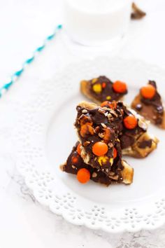 three pieces of chocolate candy bark on a white plate next to a glass of milk