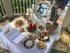 a table topped with lots of food and an open book on top of a white table cloth