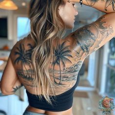 a woman with tattoos on her back standing in front of a kitchen counter and looking at the ocean