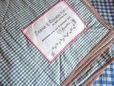 a blue and white checkered bed spread with embroidered name on it