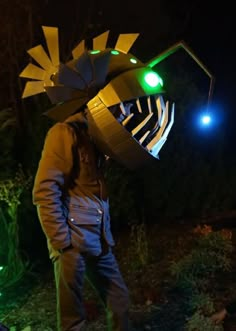 a man standing in front of a green light with a large metal object on his head