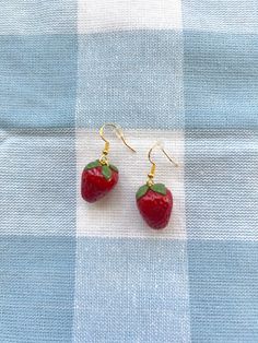 two small red strawberries sitting on top of a blue and white checkered cloth