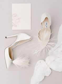 the shoes are all white and have feathers attached to each shoe, along with an envelope