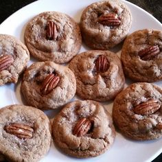 a white plate topped with chocolate chip cookies covered in pecans