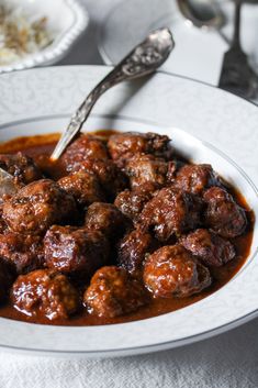 a white bowl filled with meatballs and sauce