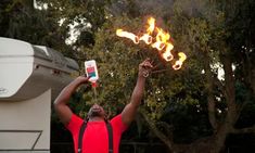 a man holding up his cell phone in the air with flames coming out of it