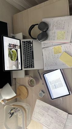 an overhead view of a desk with two laptops, papers and headphones on it