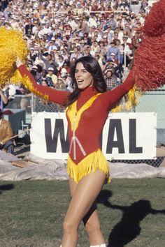 a woman in a yellow and red cheerleader outfit holding a pom - pom