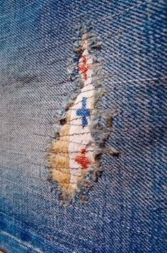 the back side of a pair of blue jeans with torn up patches on it and a red white and blue design