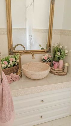 a bathroom sink sitting under a large mirror next to a potted plant on top of a counter