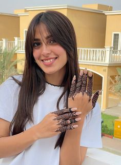 a woman with henna on her hands smiling and showing off her hand tattoo designs