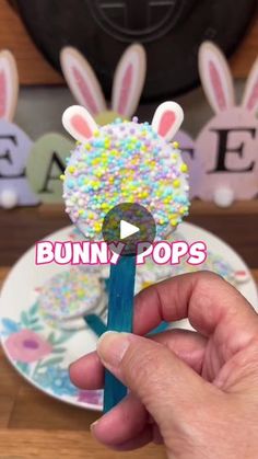 a person is holding up a bunny pops stick with sprinkles on it