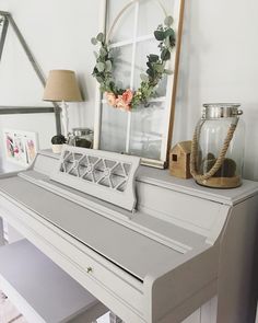 a white piano sitting on top of a wooden floor next to a mirror and lamp