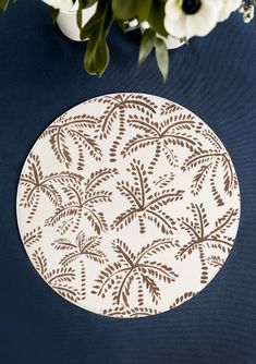 a white plate sitting on top of a table next to a vase filled with flowers