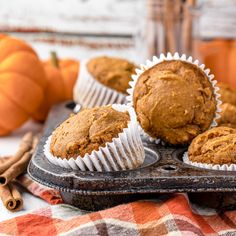 several muffins on a tray with cinnamon sticks and pumpkins in the background