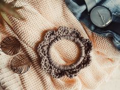 a crocheted ring sits on top of a blanket next to a button and some other items