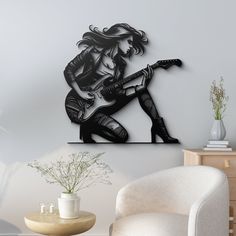 a black and white photo of a woman playing the guitar on a wall above a chair