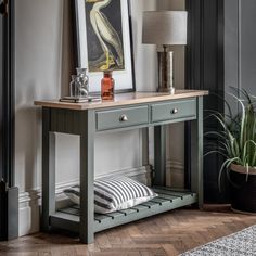 a table with a lamp and some pictures on it in a room that has hardwood floors