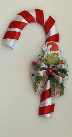 a candy cane with the grinch on it's side is hanging from a wall