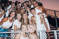 a group of young people standing next to each other in front of a metal fence