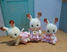 three small stuffed animals sitting next to each other on top of a counter in front of a blue door