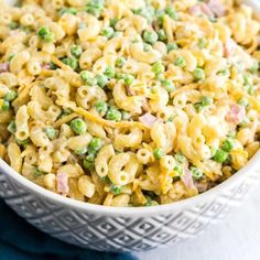 a white bowl filled with macaroni and peas on top of a blue towel