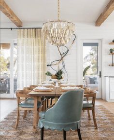 a dining room table with chairs and a chandelier hanging from the ceiling above it