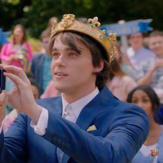 a man in a blue suit takes a photo with his cell phone while people watch