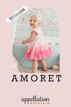 a baby girl wearing a pink and white dress with the words amoret on it