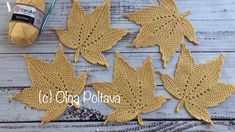 four crocheted leaves sitting on top of a wooden table next to a ball of yarn