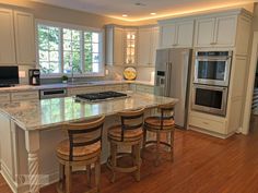 a kitchen with white cabinets and marble counter tops