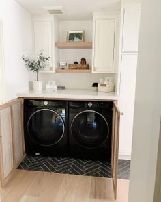 a washer and dryer in a small room with white cupboards on the wall