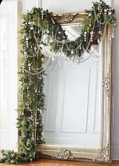 a mirror sitting on top of a wooden floor next to a christmas wreath and garland