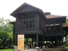 an old wooden building with people sitting on the porch and standing in front of it