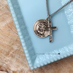 a silver cross on a blue plate with a chain hanging from it's center