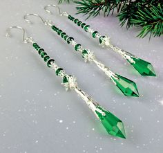 three green crystal earrings hanging from a christmas tree