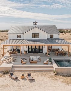 a large white house with a pool in the front yard and patio furniture around it