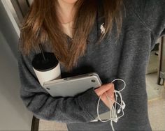 a woman holding a tablet and cup with headphones in her hands while looking at the camera