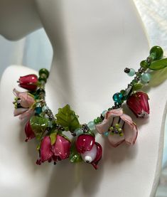 One of a kind Flower Garden Necklace. Designer Handmade Original. Exquisite handmade glass flowers. Extraordinarily lifelike flowers and leaves of Rose Red, Pink and Green glass. are truly an art form. The flowers are roses, fuschias and tulips. One of the larger light pink roses was accidentaly broken in the making of the necklace but I repaired it and it's very difficult to see the place. I have combined the flowers and leaves with natural green garnets and green glass beads.  Sterling silver hook clasp and decorative beads. This would be a stunning gift for a woman who loves to garden. I think this is one of the prettiest necklaces I have ever made. I love looking at it. When it's not being worn it should be displayed like a piece of art. There is only one. Green Pink Flowers, Light Pink Roses, Designer Glass, Valley Village, Light Pink Rose, Decorative Beads, Green Garnet, Pretty Necklaces, Glass Flowers