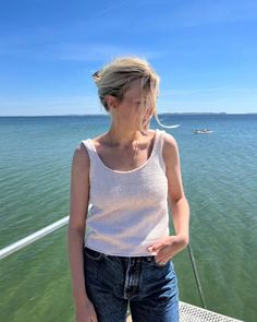 a woman is standing on a dock near the water and looking at something in the distance