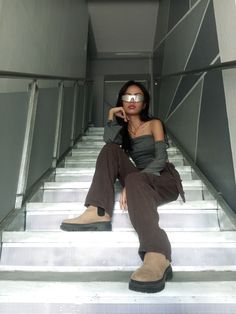 a woman sitting on some stairs with her leg up and wearing sunglasses over her eyes