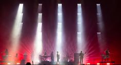 a group of people standing on top of a stage under spotlights in the dark