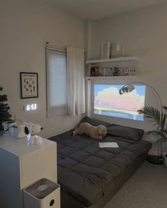 a bed room with a neatly made bed next to a window and a tv on the wall