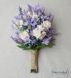 purple and white flowers are tied to a burlocked bridally bouquet