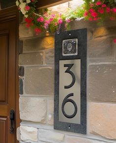 a house number sign with flowers hanging from it's side