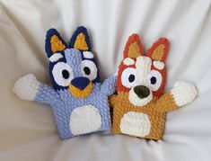 two crocheted stuffed animals sitting next to each other on a white sheet,