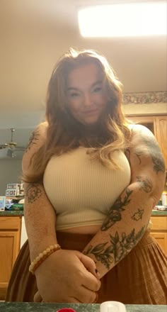 a woman standing in front of a counter with tattoos on her arms