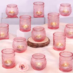 many pink glass cups and candles on a table