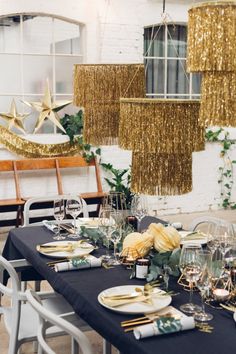 a table set up for a party with place settings and hanging chandeliers in the background